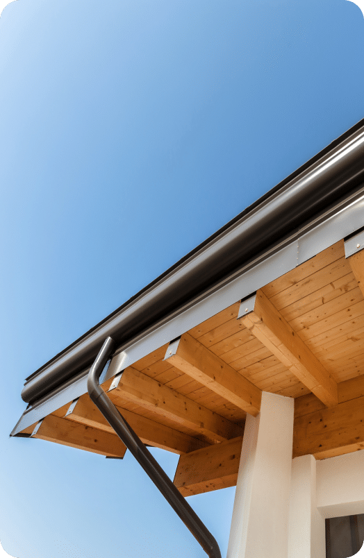 Photo of black gutter from below with a sunny blue sky in the background
